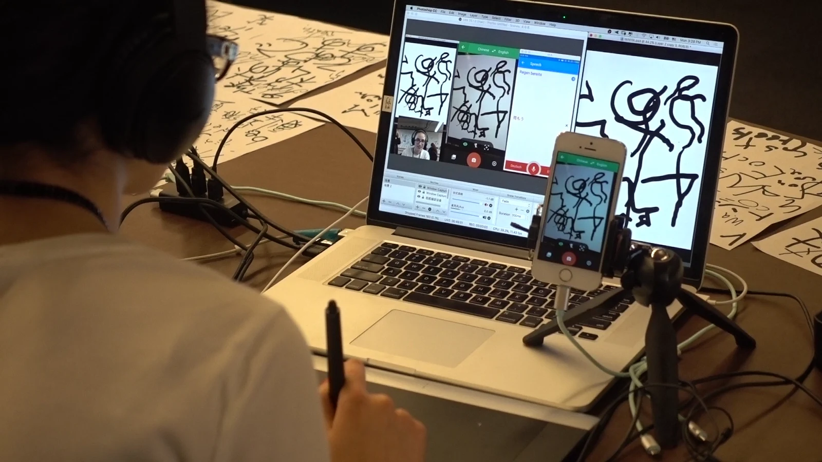 参与者在纸张前操作手机，旁边电脑显示文字和图形